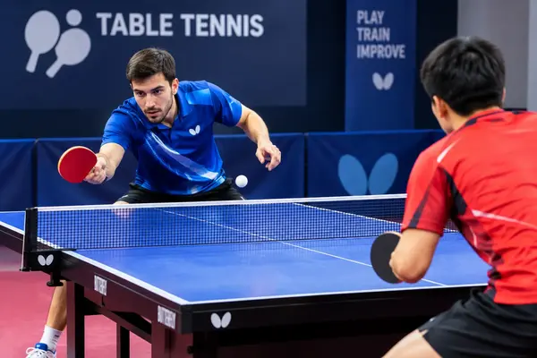Table tennis players competing in an indoor match